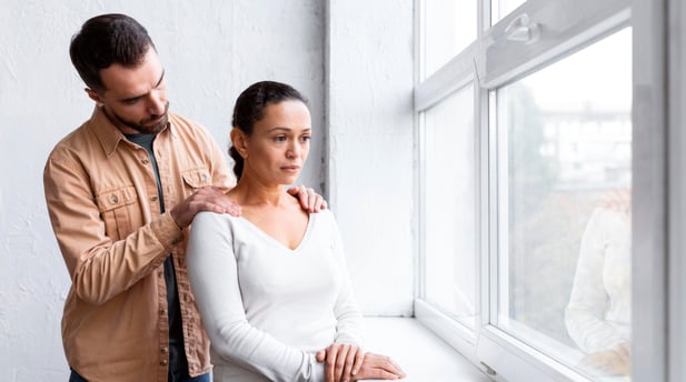 man-consoling-sad-woman-group-therapy-session-while-looking-through-window